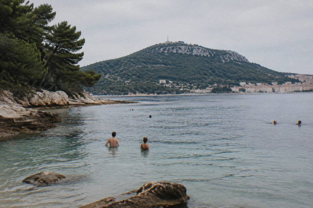 Swimmers in shallow water at a Split bay with the Marjan hill in the background