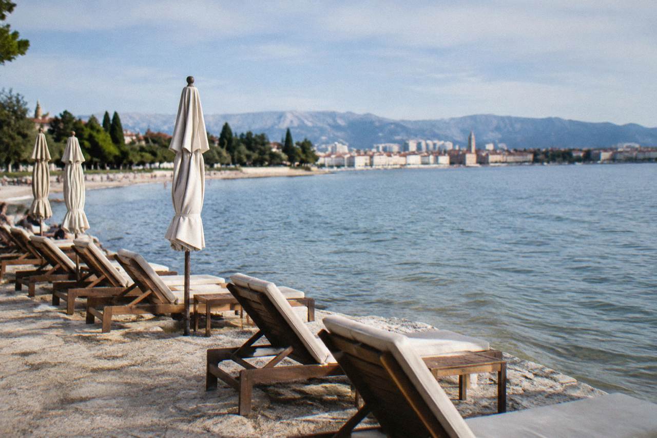 Sun loungers on a stone beach in Split under a clear autumn sky