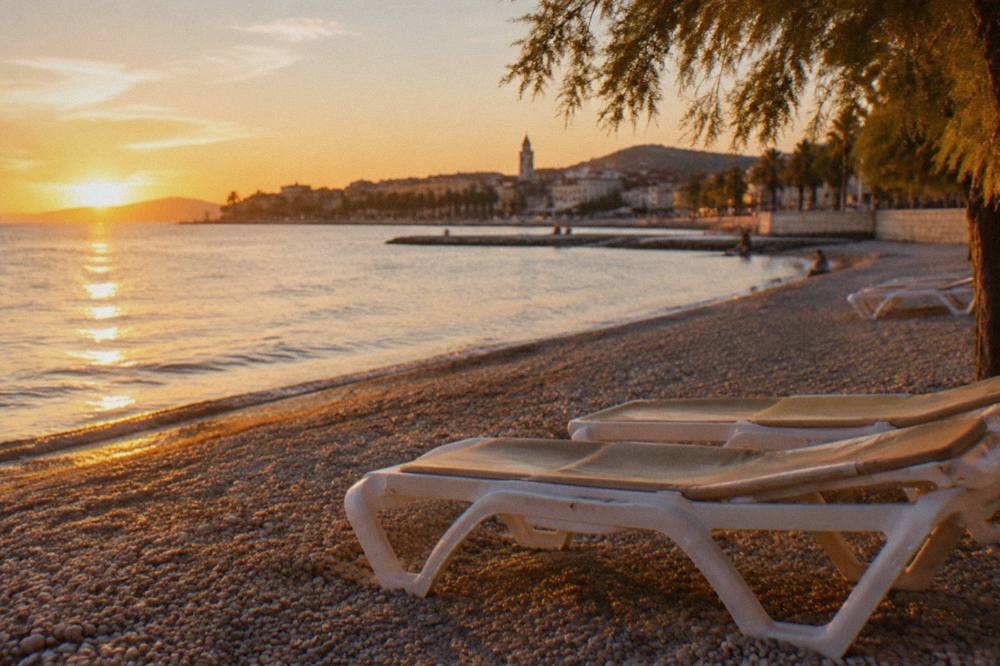 An autumn afternoon on a pebble beach near Split with calm sea and empty loungers