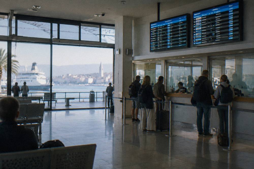 A ferry ticket hall in Split with departure boards and passengers at the counter
