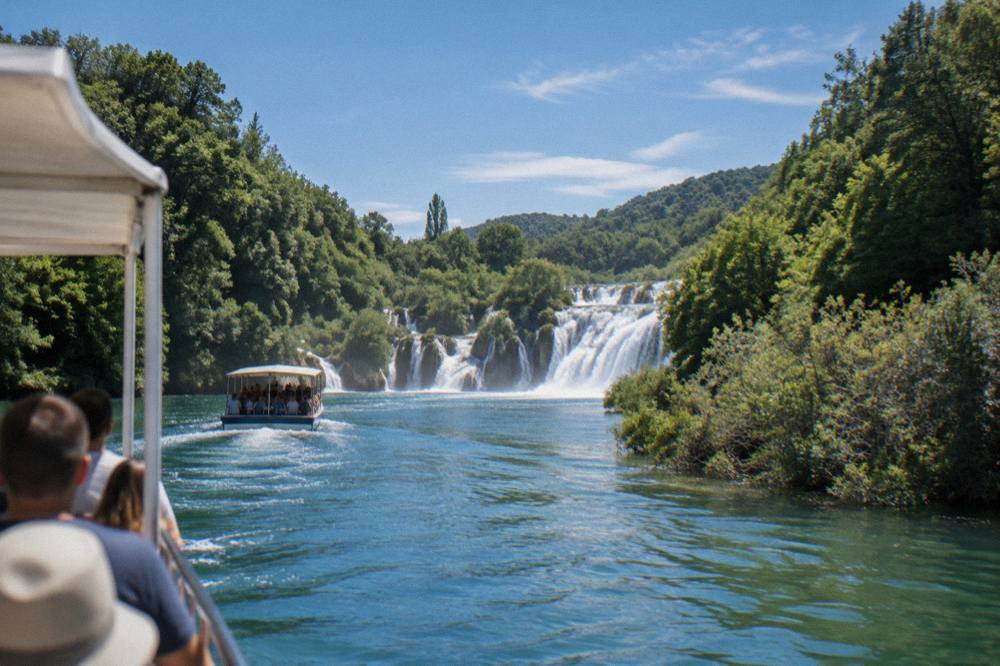 A boat carrying visitors along the Krka river toward the waterfalls between tree-covered banks