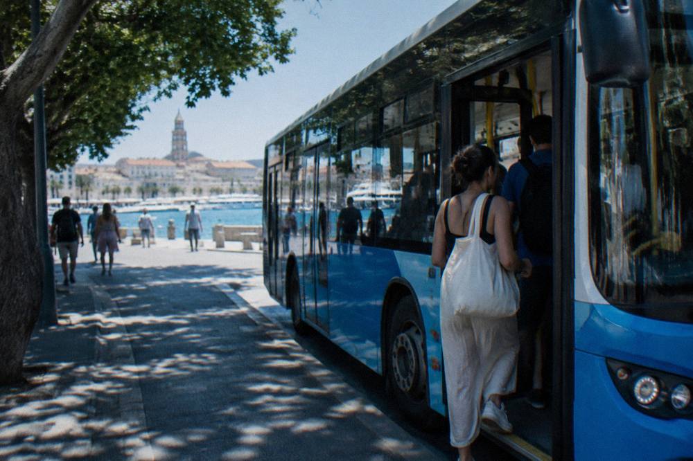 A passenger boarding a local bus at a stop in central Split in summer