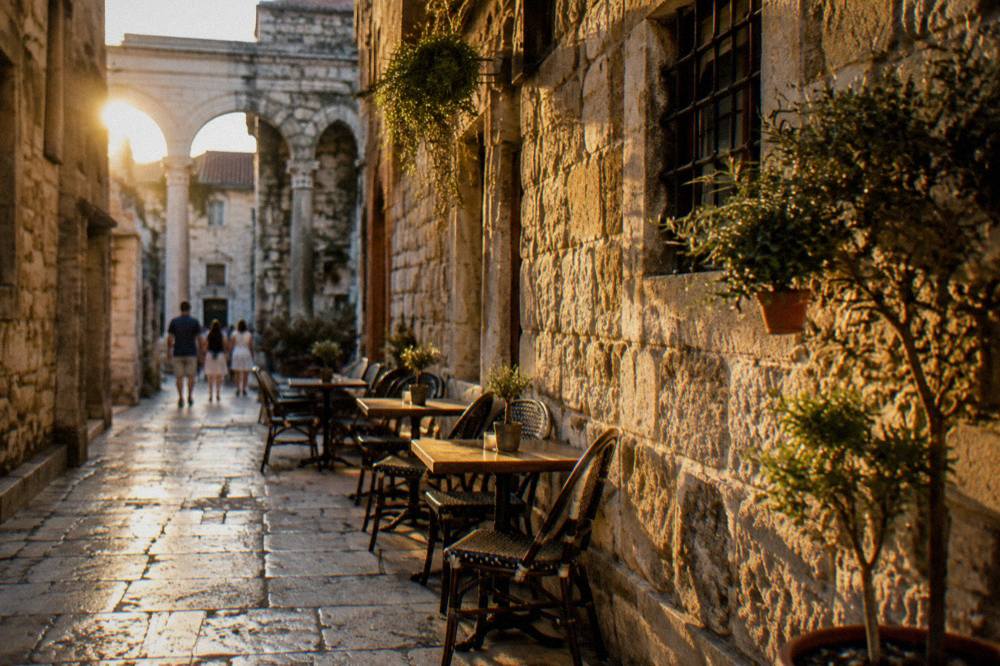 Stone alleys inside Diocletian's Palace in Split with cafe tables along an old wall
