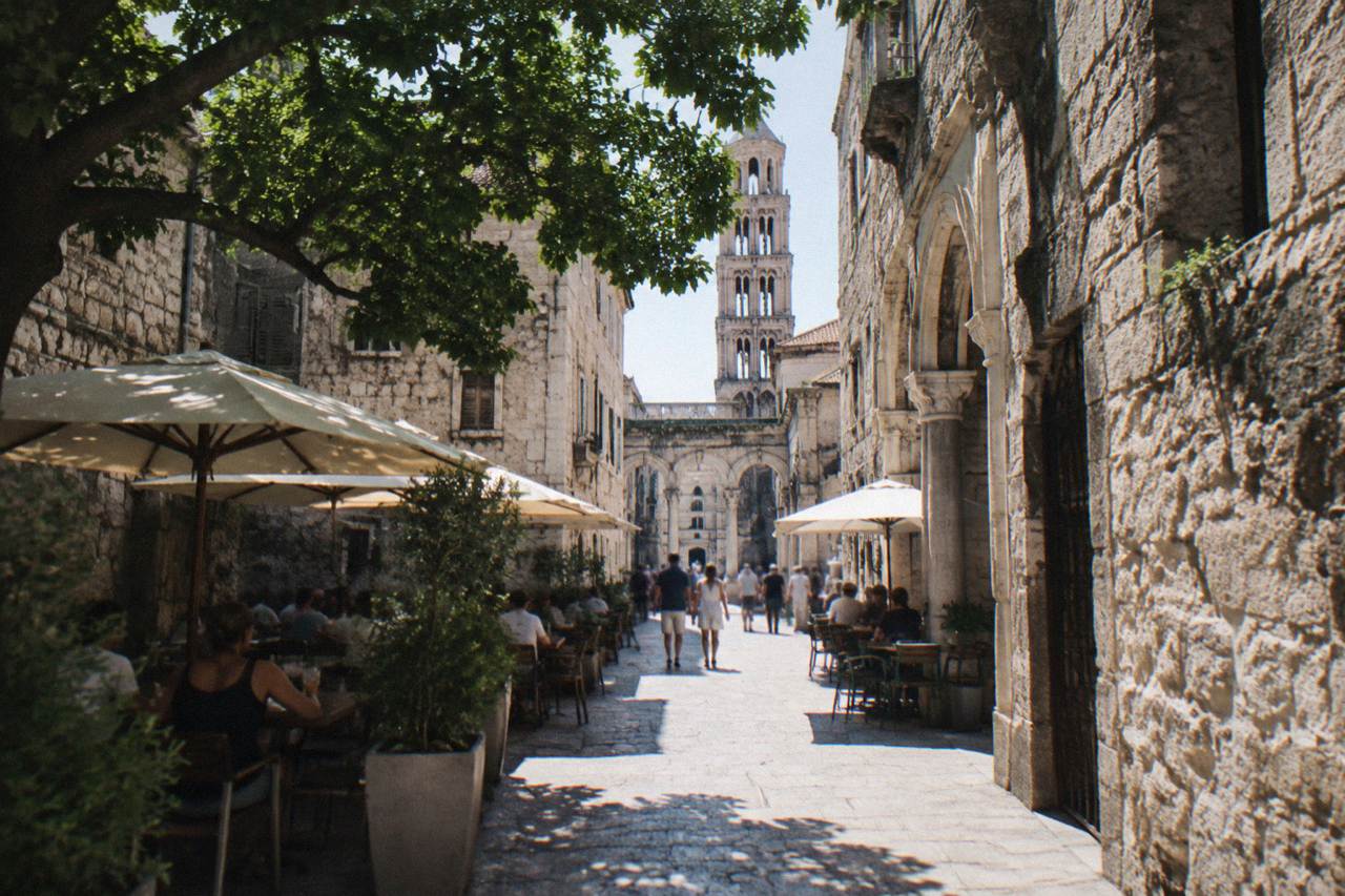 A narrow stone street inside Diocletian's Palace in Split with cafés and pedestrians
