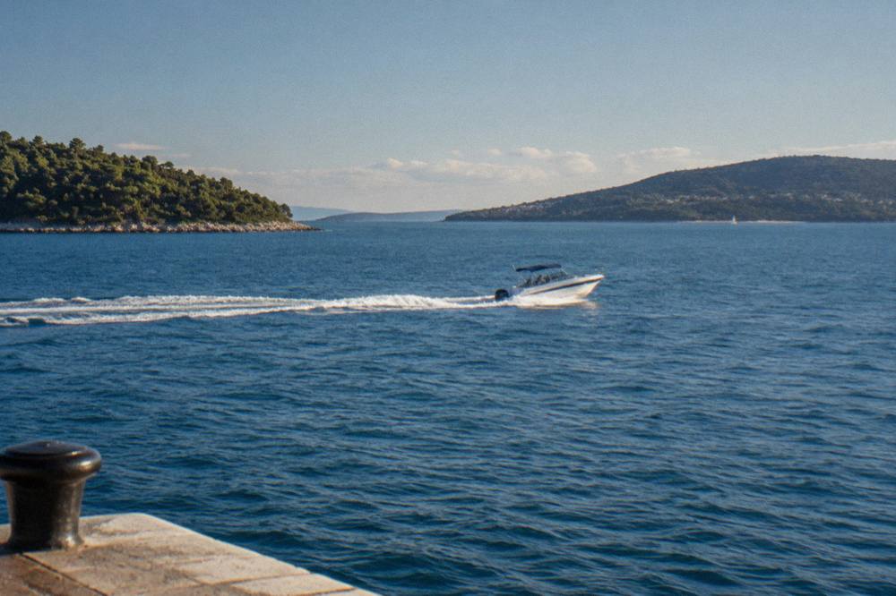 A speedboat crossing open blue Adriatic water between islands on a sunny morning