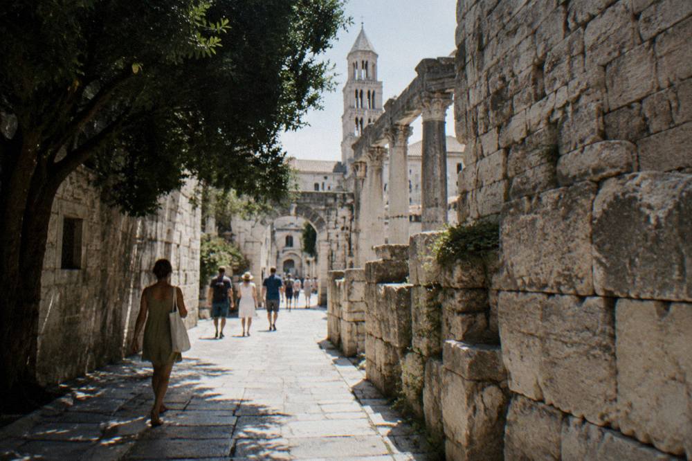Pedestrians walking a narrow stone lane inside Diocletian's Palace in Split