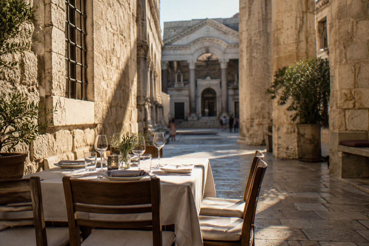 A table set for dinner beside the stone walls of a palace courtyard in Split