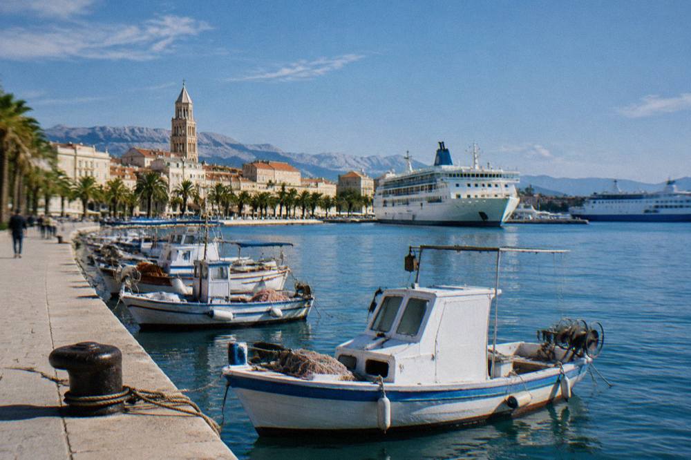 Fishing boats and ferries moored along the Split waterfront promenade in morning light