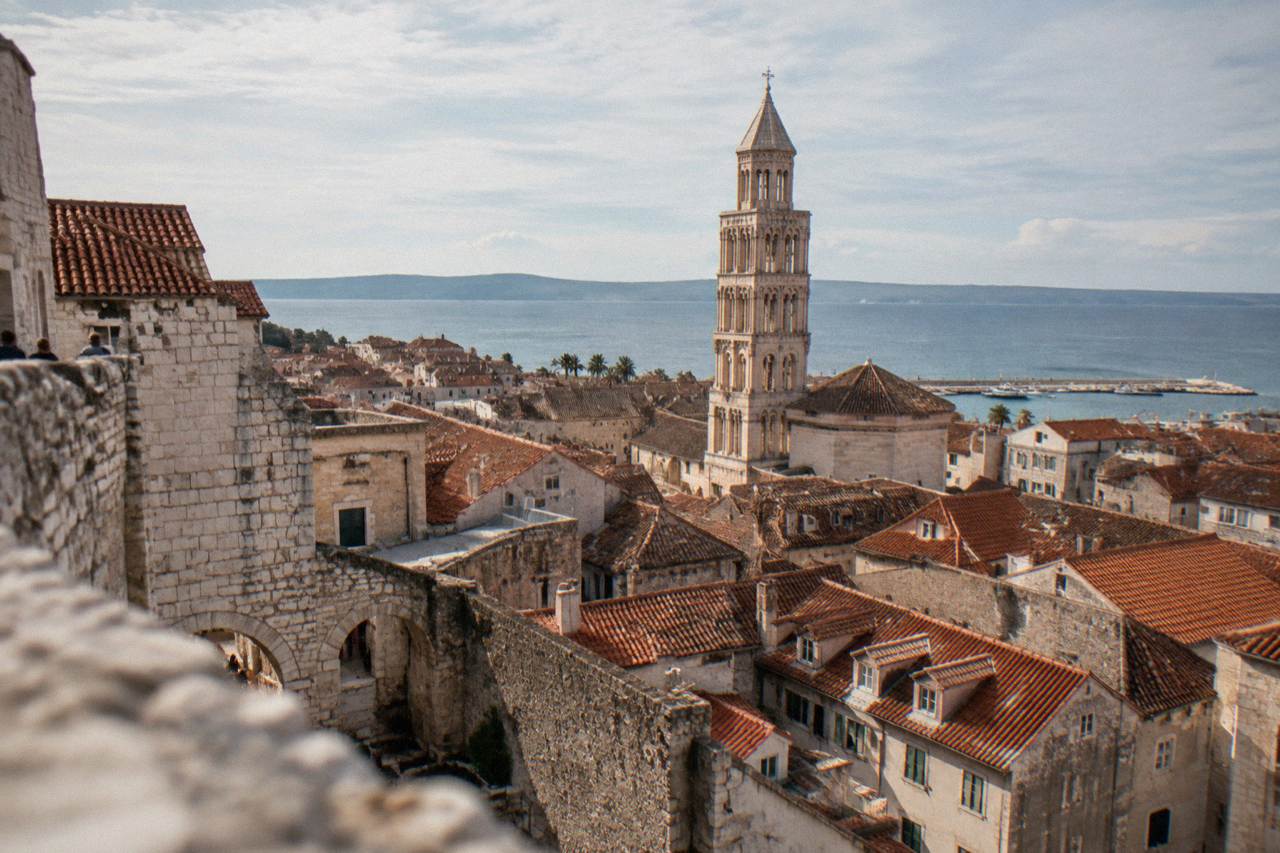 Rooftops and stone buildings of Split Old Town seen from above with the Adriatic Sea in the distance
