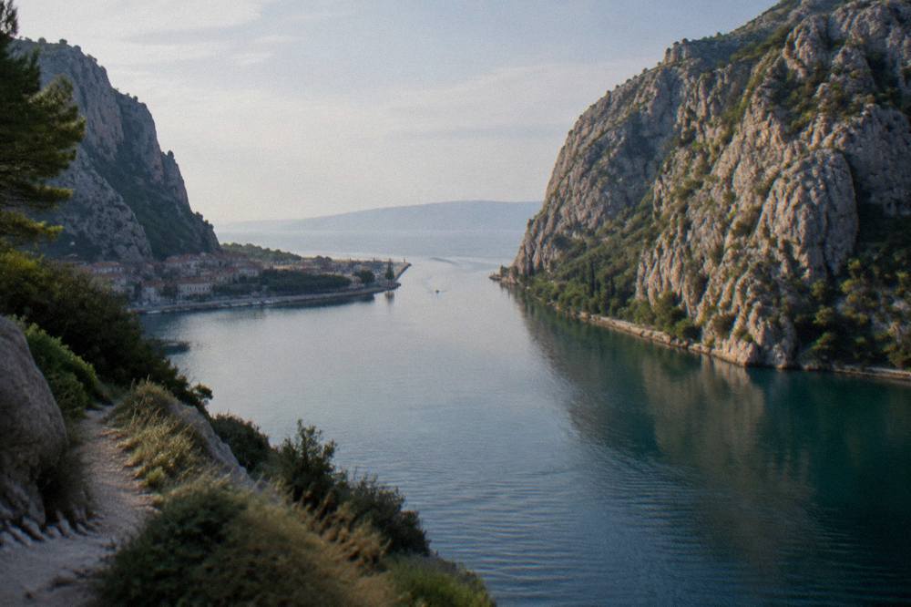 A river mouth opening between steep canyon cliffs toward the sea