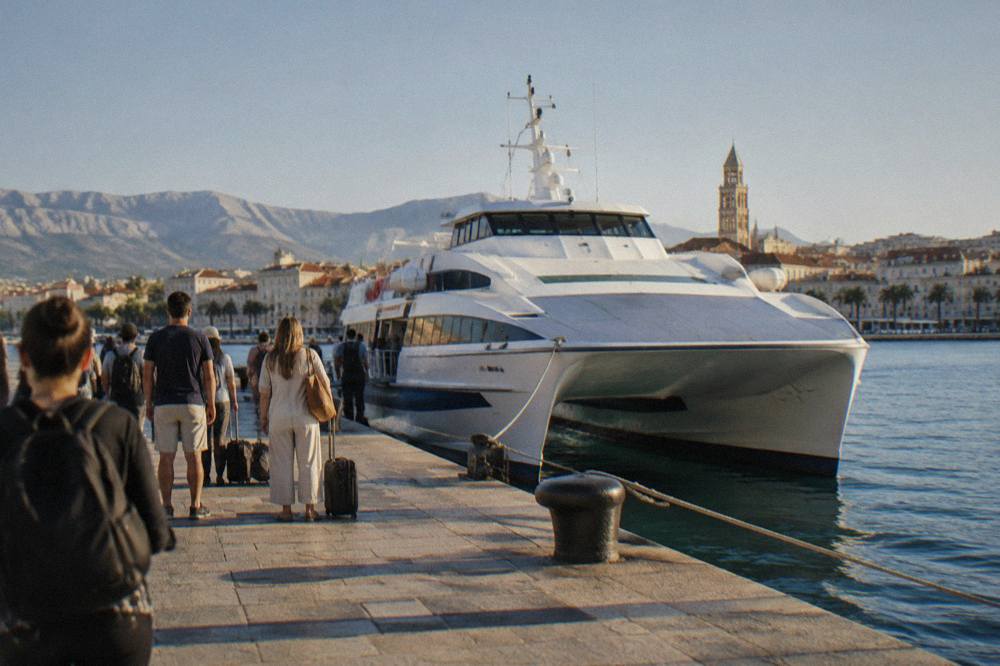 Passengers waiting beside a fast catamaran moored at a city harbour quay in the morning