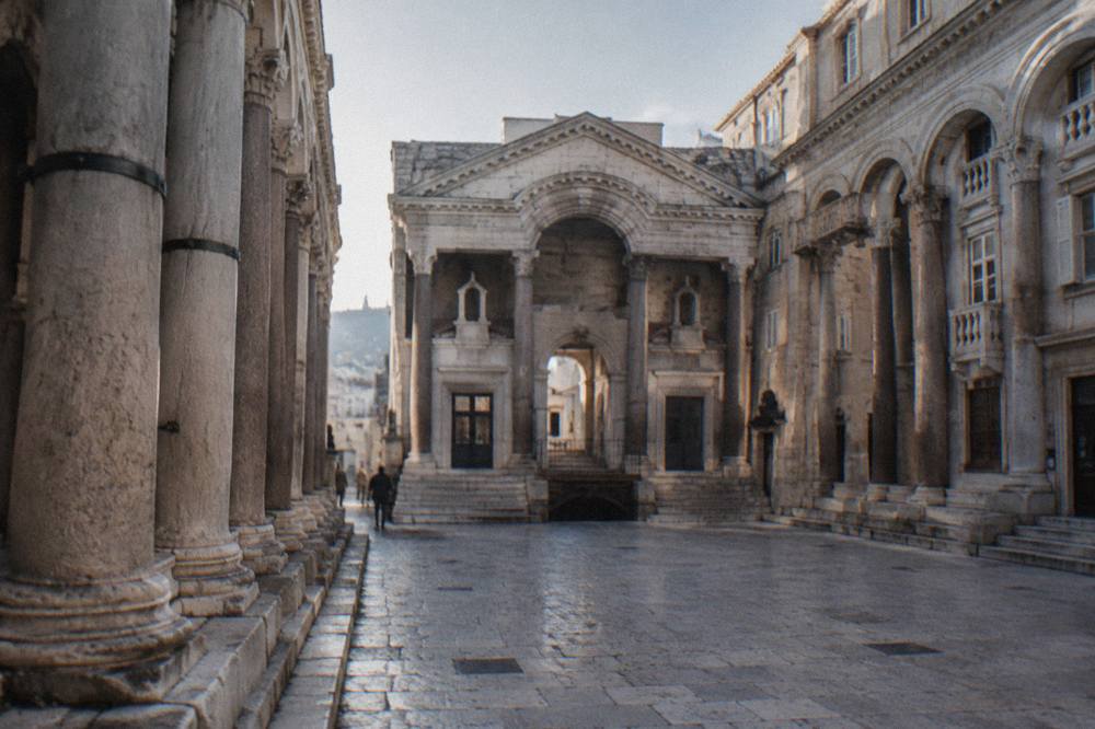 The Peristyle square of Diocletian's Palace with its stone columns and surrounding old buildings in daylight