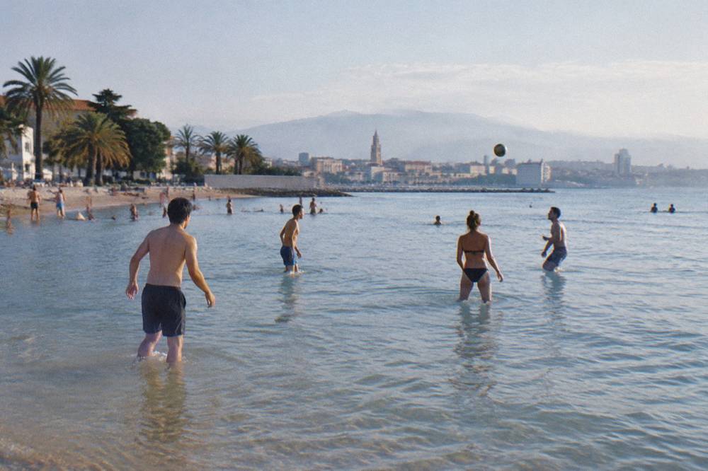 People playing a ball game in shallow sandy water at a city beach