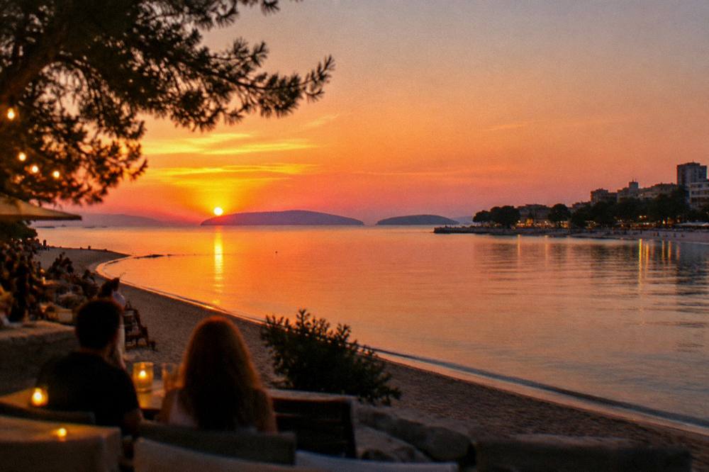 Evening view over a sandy bay with cafe lights and calm water