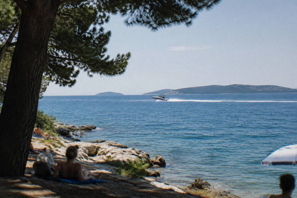 A speedboat cutting across open water towards islands visible from the Split coast