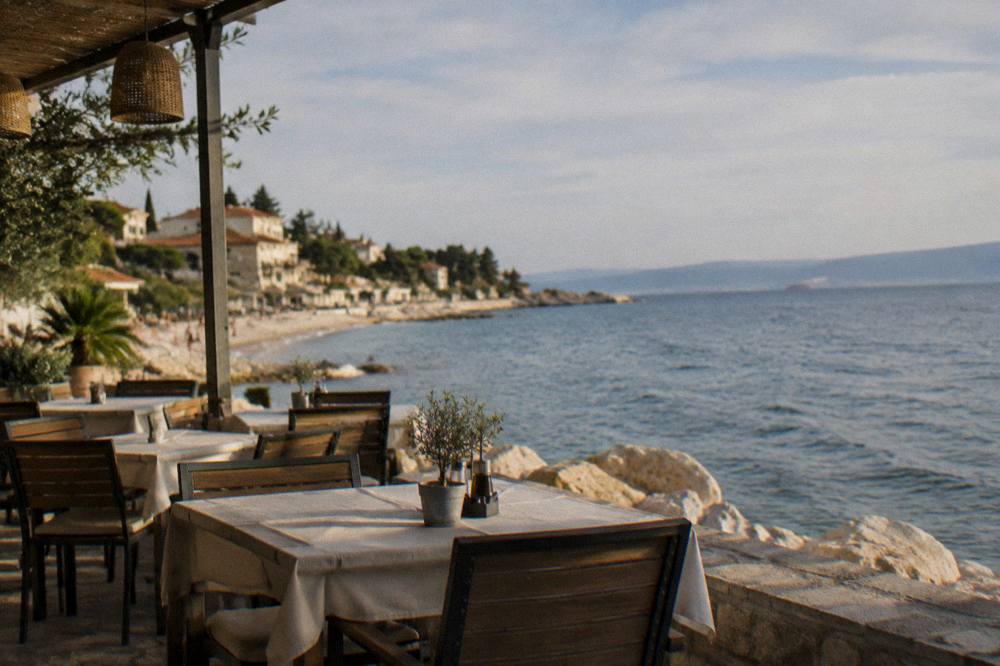 A waterfront restaurant terrace with tables beside the sea in Stobrec