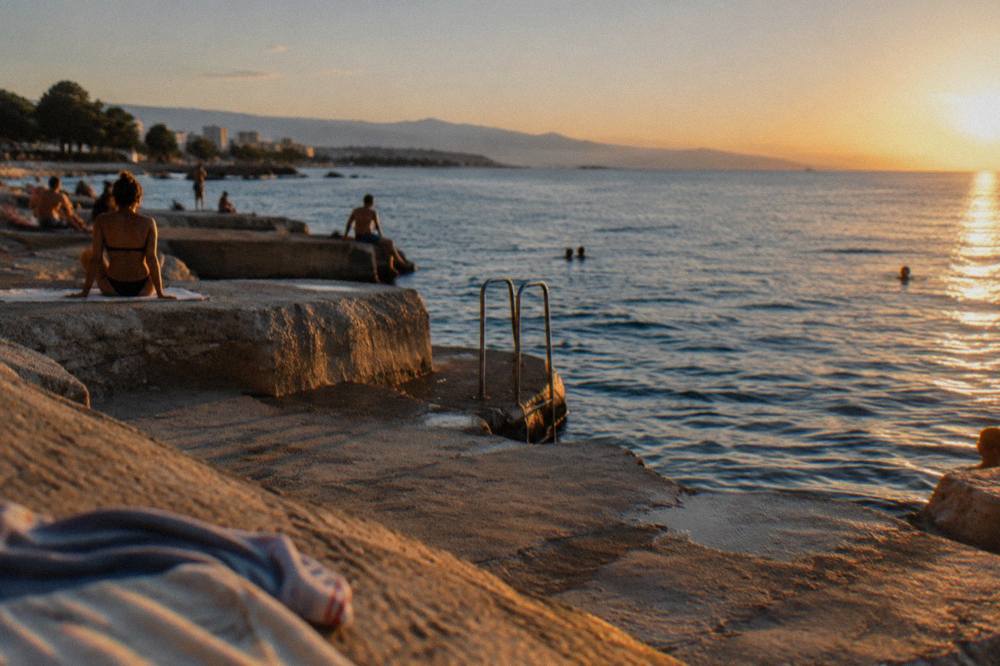 Concrete swimming terraces at Žnjan with bathers on the ledges and calm blue Adriatic water