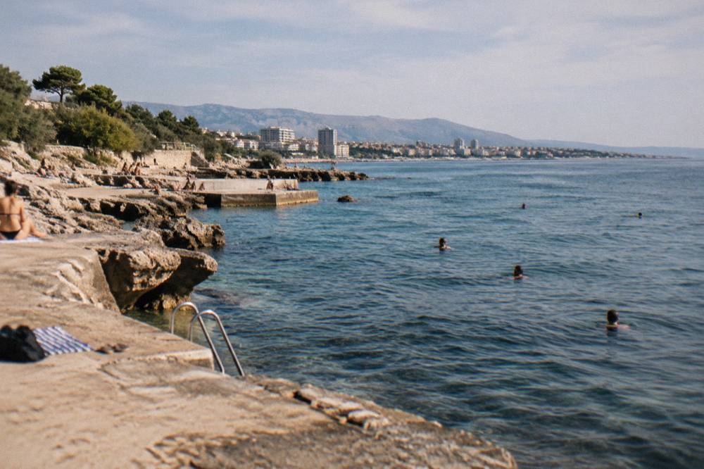 Morning light across the Žnjan plateau in Split with swimmers in the water off the concrete ledges