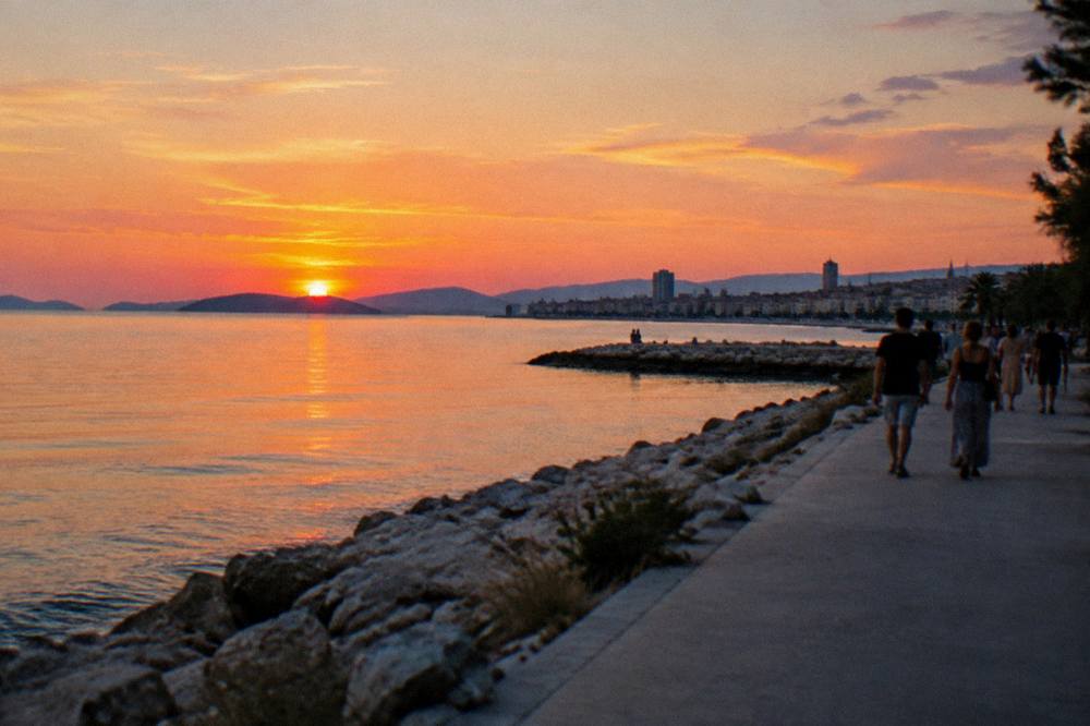 People strolling the seaside promenade at Žnjan in Split toward the city skyline at dusk