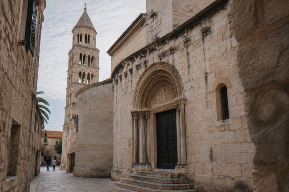 The stone facade and Romanesque doorway of the Cathedral of Saint Domnius seen from a narrow lane in Split