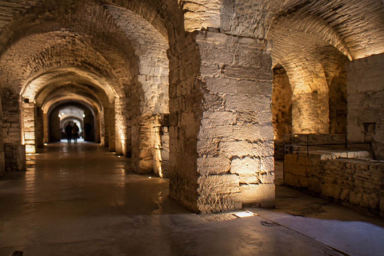Vaulted stone corridors of ancient Roman cellar rooms lit by warm lights