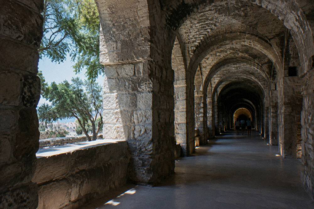 Rows of stone arches receding down a dim ancient hallway