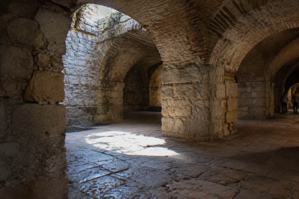 Sunlight falling through an opening onto ancient stone paving in a cellar room