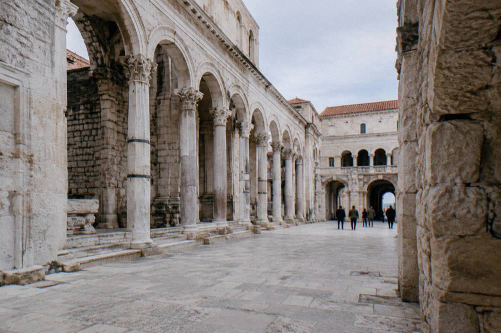 A wide square of white stone arcades beside the palace in afternoon light