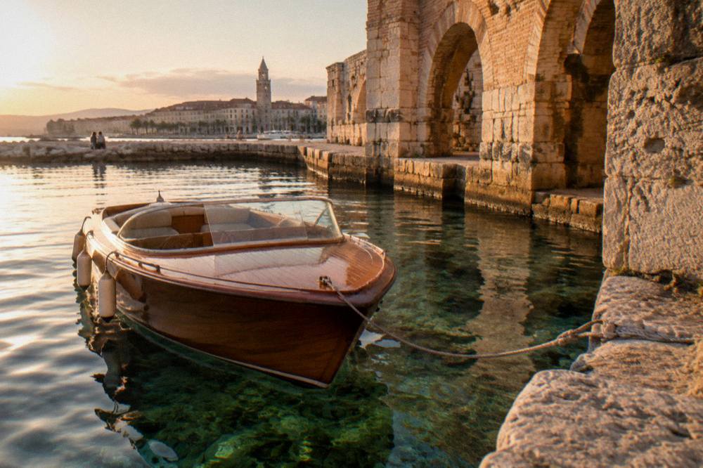 A wooden speedboat moored in a small Dalmatian bay with clear water