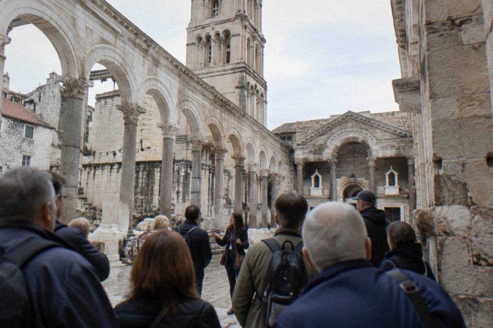 Tour group gathered in a stone courtyard of the old palace listening to a guide