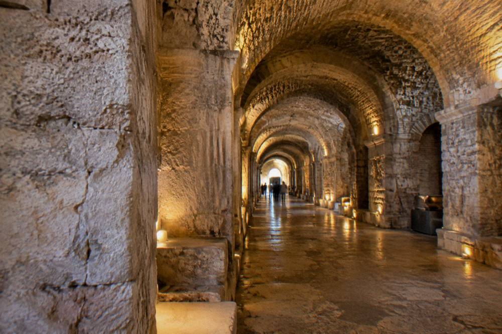 Barrel-vaulted stone halls of the palace substructures lit by warm lamps