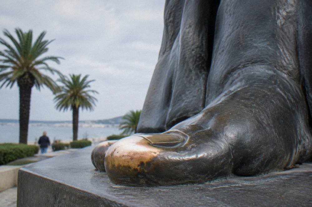 Close view of the bronze toe of the Gregory of Nin statue, polished smooth and shining against the dark metal