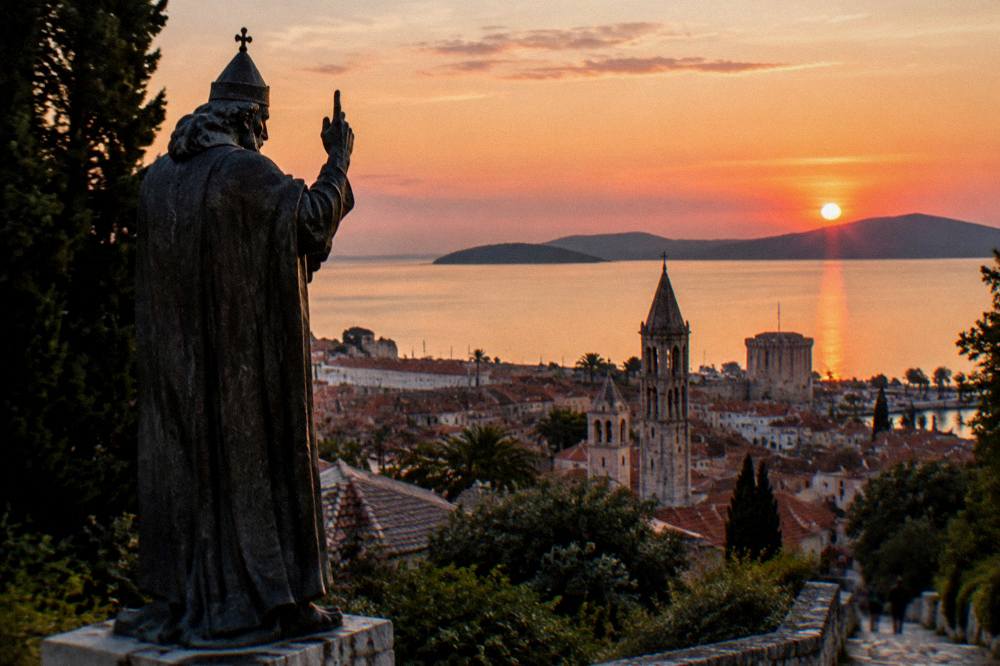 Sunset over the rooftops and stone towers of Split Old Town seen from a hillside path