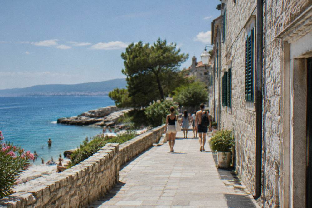 A stone street in the old town with people dressed in summer clothes walking