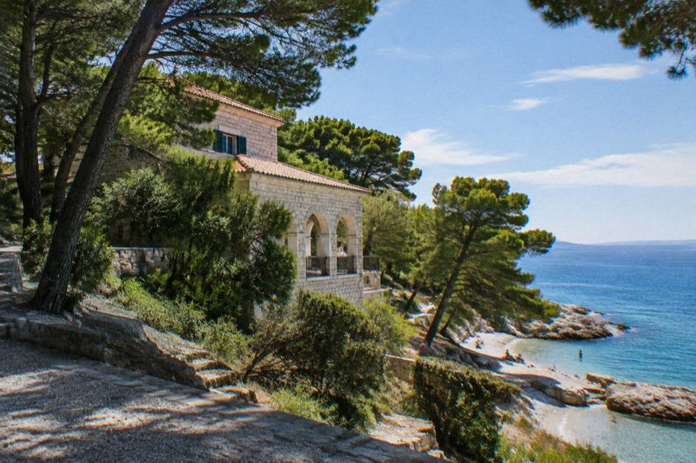 A stone villa gallery building surrounded by pine trees near the coast