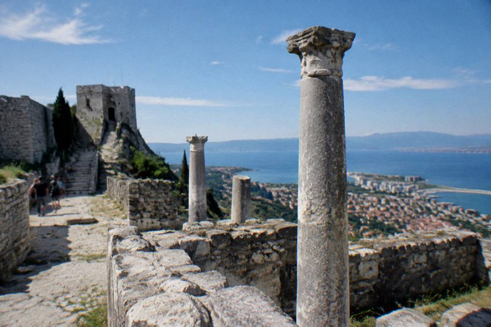 Ancient stone ruins and columns under open sky on the edge of a modern town