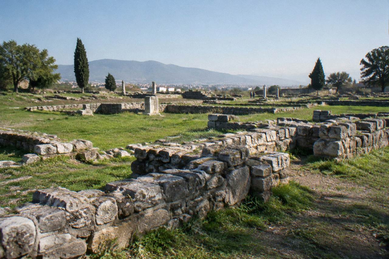 Roman stone walls and grassy foundations of the Salona archaeological site under a blue sky