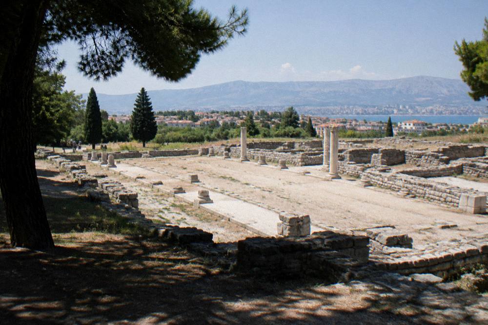 Wide view across the excavated basilica foundations at Salona with Split suburbia in the distance
