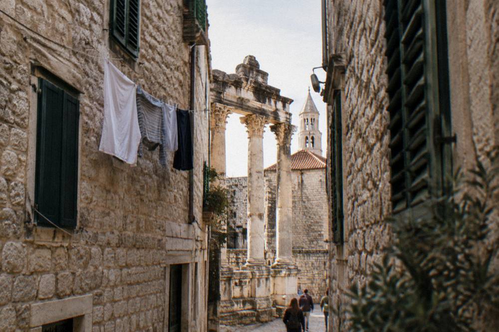 A narrow stone alley in an old Mediterranean town with laundry and shuttered windows