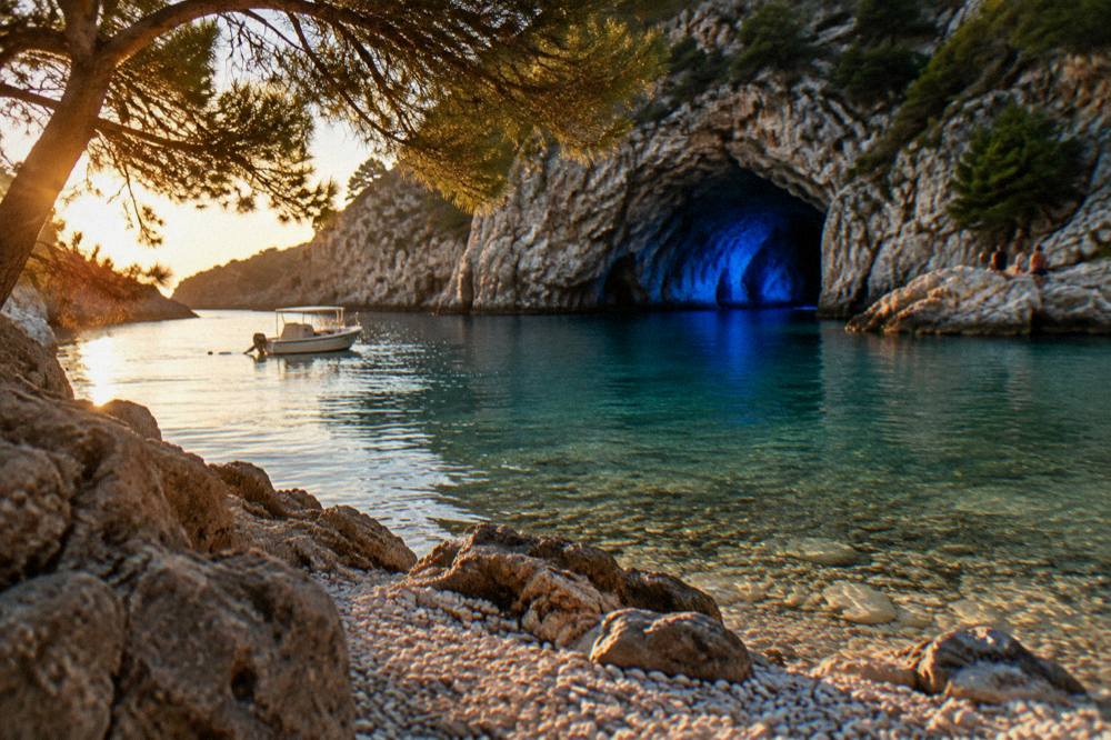 A quiet island cove with pebbles, clear shallow water and pine trees