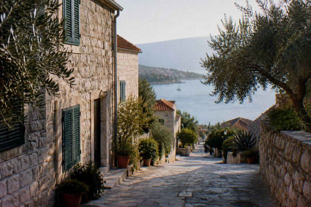 A stone village street on a Dalmatian island with olive trees and shutters
