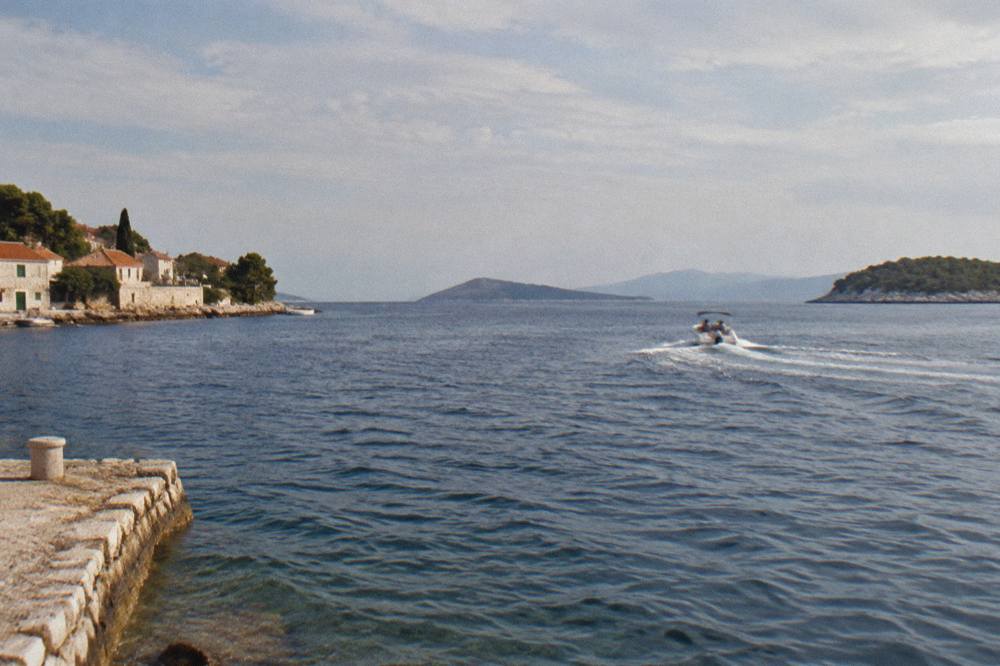 A speedboat crossing open water toward distant islands