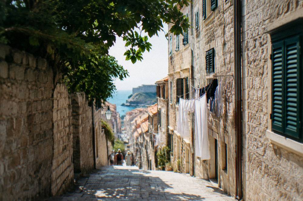 Narrow stone street in Dubrovnik old town with shutters and laundry lines