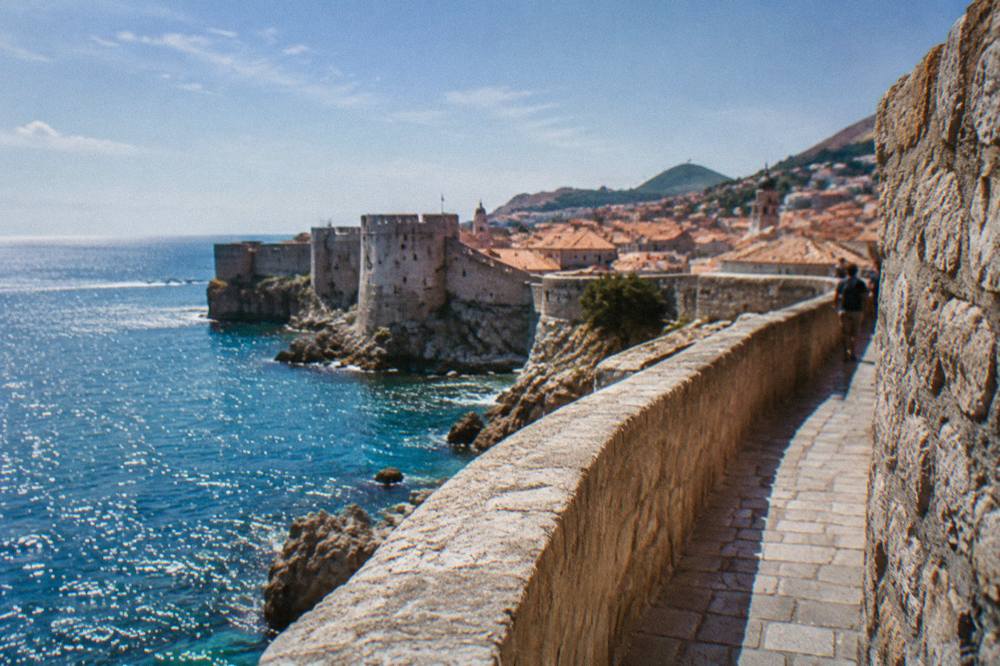 Sunlit section of Dubrovnik city walls above the sparkling Adriatic in late afternoon