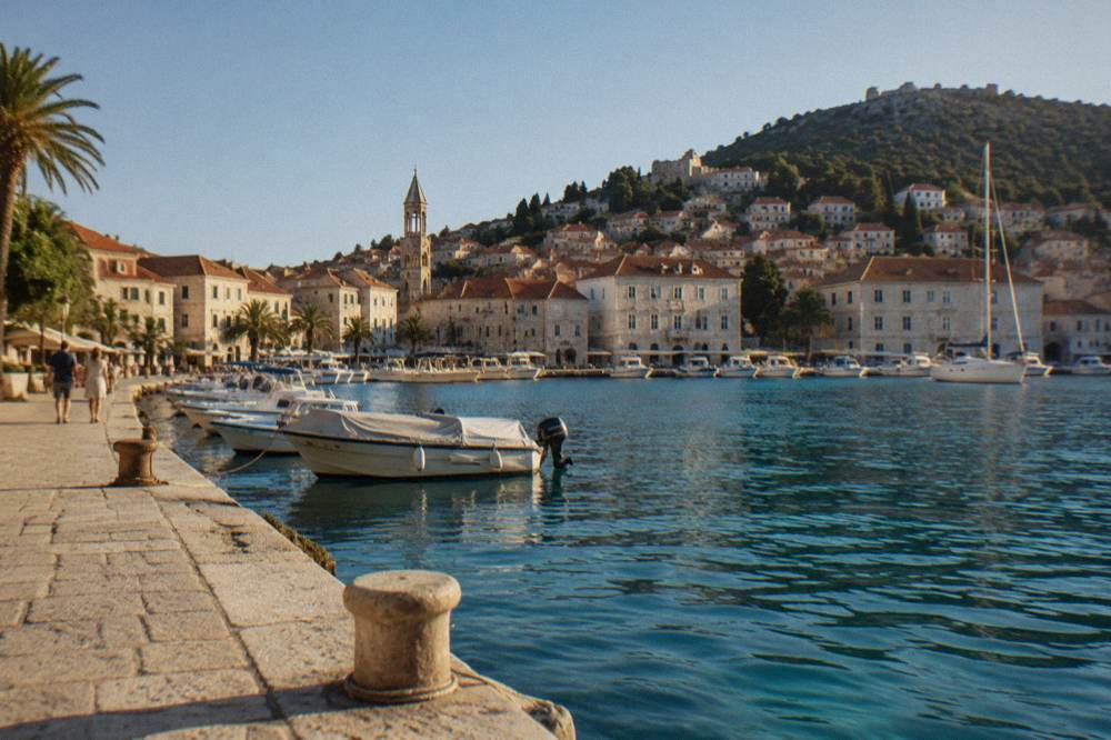 Stone buildings of a small Dalmatian town rising from a turquoise harbour with moored boats