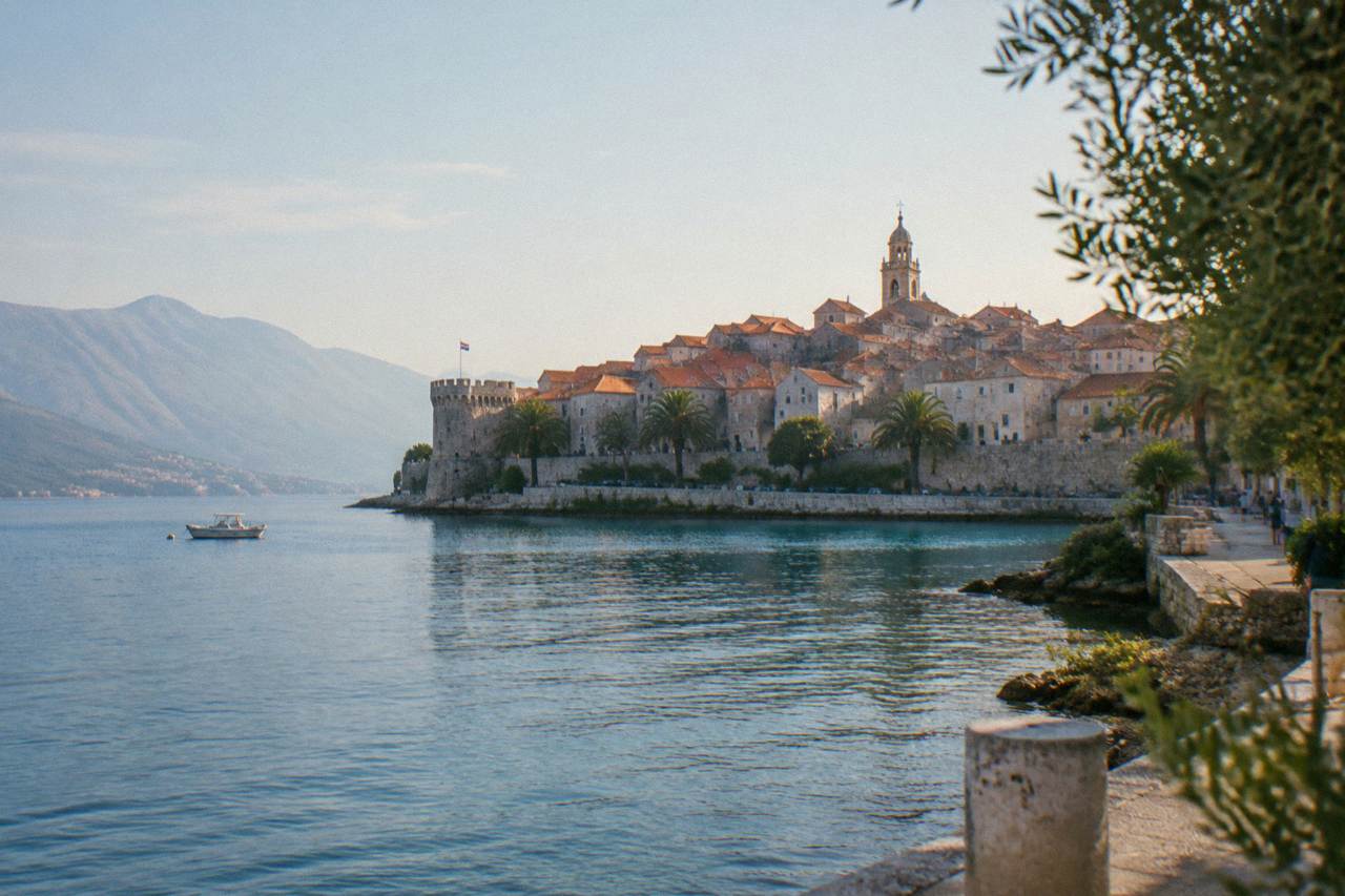 A stone walled town on a Croatian island rising above calm blue Adriatic water