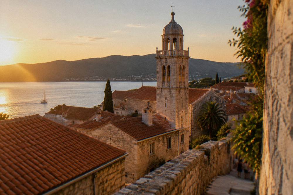 A stone tower and tiled roofs of an island old town at golden hour
