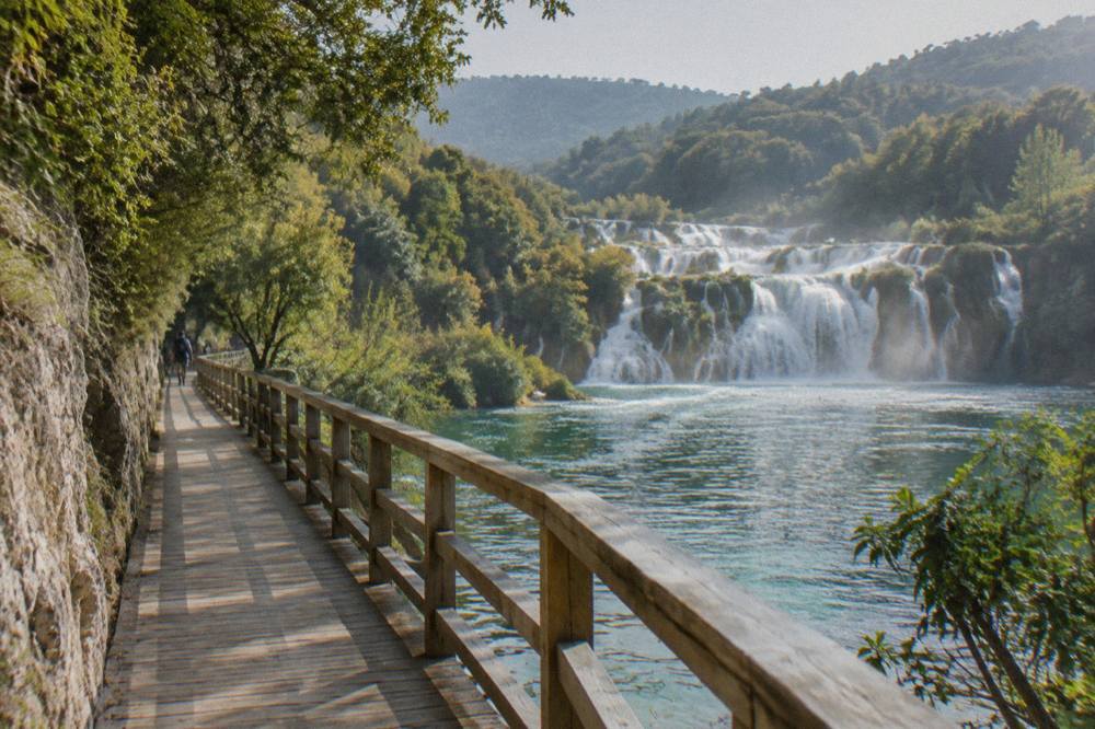 Wooden walkway leading along a river canyon toward a waterfall