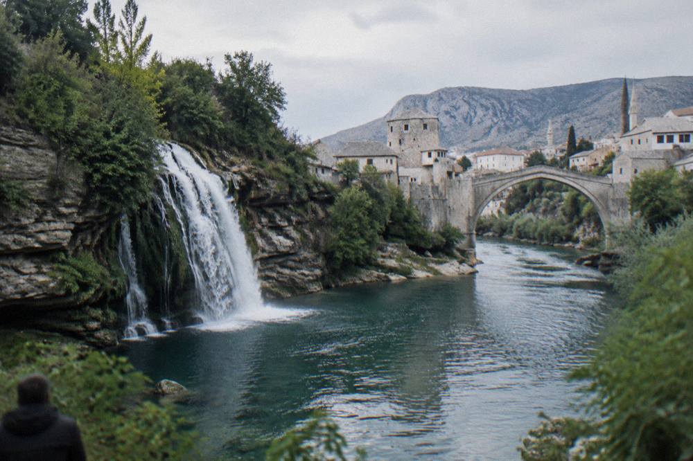 Waterfall cascading into a wide natural pool ringed by green cliffs