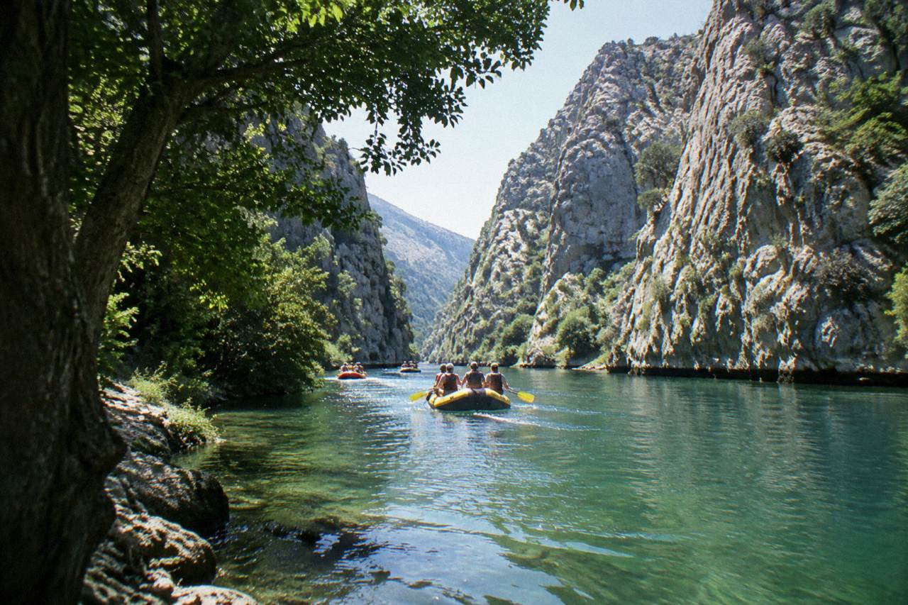 Rafts floating down a clear green river between tall rocky canyon walls